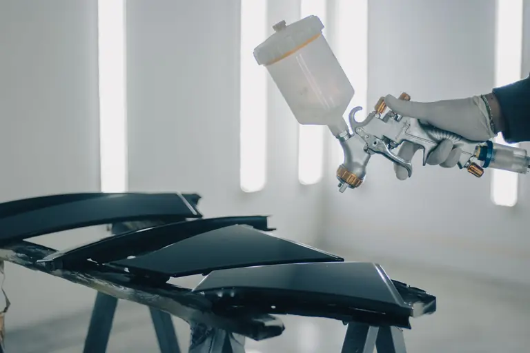 Pistolet de peinture appliquant une teinte sur un élément de carrosserie
